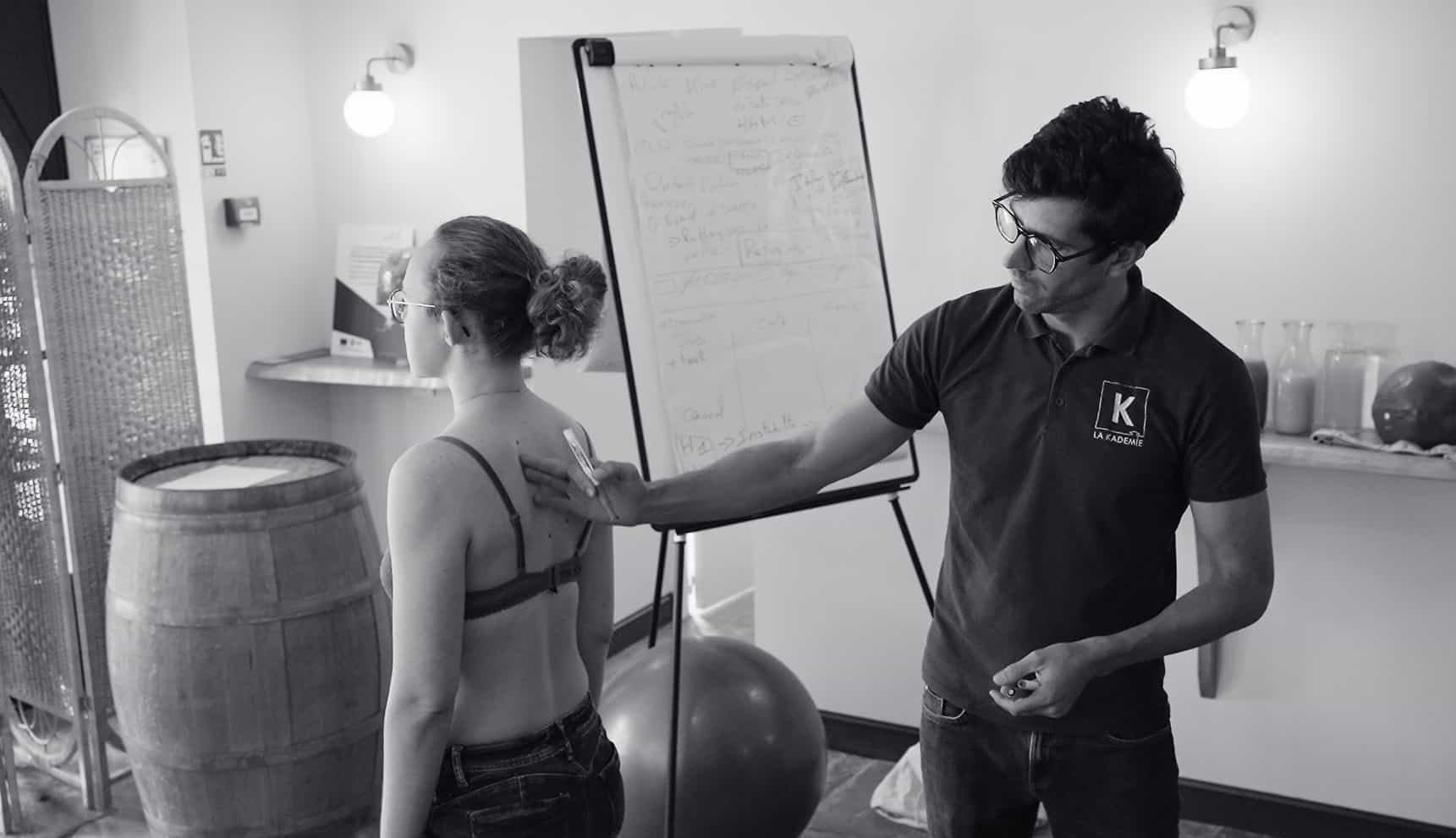 Photo en noir et blanc d'un formateur en kinésithérapie manipulant le dos d'une patiente